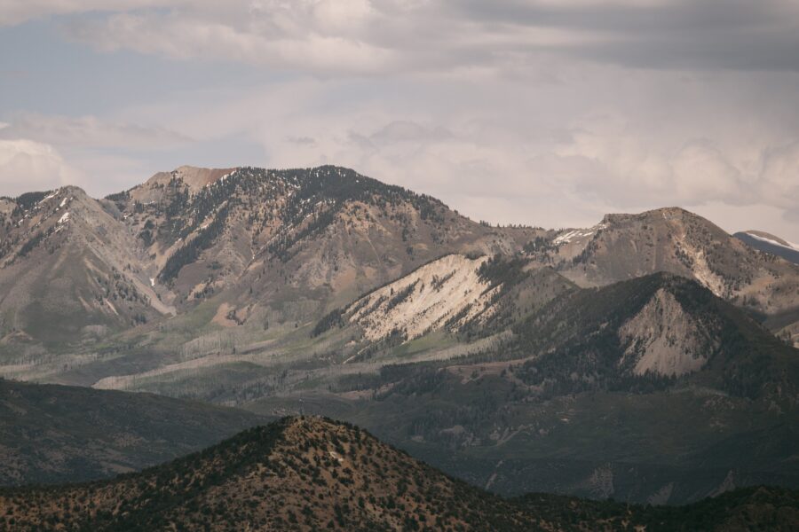 Scenic view of rugged mountains under cloudy skies, showcasing a mix of greenery and rocky terrain, indicative of a diverse ecosystem and natural beauty in a mountainous region.